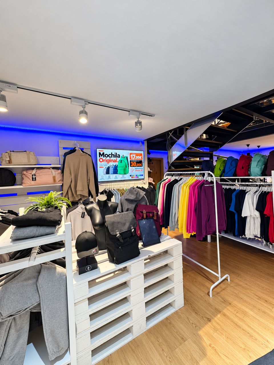 Televisor colgado en la pared interior de una tienda de ropa, mostrando una promoción